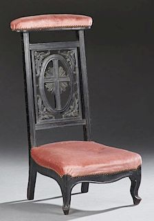 French Carved Ebonized Beech Prie Dieu, c. 1870, the upholstered arm rest over a floral and cross carved back splat, to a bow