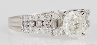 Lady's Platinum Dinner Ring, with a central 1.14 carat round diamond flanked by diamond mounted lugs, the shoulders of the ri