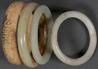 FOUR CHINESE CARVED JADE AND HARDSTONE BRACELETS