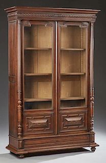 French Henri II Style Carved Walnut Bookcase, c. 1880, the stepped ogee crown over setback double doors with upper glazed pan