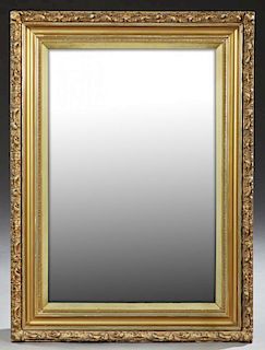 American Victorian Gilt and Gesso Mirror, c. 1900, with a relief c-scroll frame around wide cove molding and a rectangular pl
