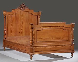 French Henri II Style Carved Pitch Pine Bed, 19th c., the arched headboard with a leaf and shield crest flanked by turned fin