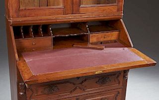 American Victorian Carved Walnut Secretary Bookcase, c. 1880, the stepped arched crown over double arched glazed doors, above