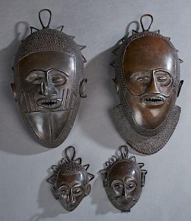 Four Benin Bronze Masks, 20th c., two large and two small, Large- H.- 15 in., W.- 8 in., D.- 5 1/2 in., Small- H.- 6 1/4 in.,