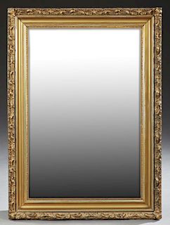 American Victorian Gilt and Gesso Mirror, c. 1900, with a relief C-scroll frame around wide cove molding and a rectangular pl