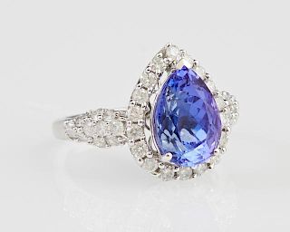 Lady's 14K White Gold Dinner Ring, with a pear shaped 3.74 carat tanzanite above a conforming border of round diamonds, the b