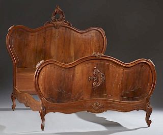 French Louis XV Style Carved Walnut Double Bed, early 20th c., the arched headboard with a C-scroll crest to a like arched fo