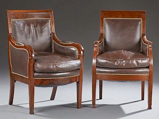 Near Pair of Carved Mahogany Leather Bergeres, c. 1840, the first with a tablet crest over an upholstered back and rounded ma