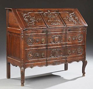 Louis XV Style Carved Oak Slant Front Secretary, 19th c., the serpentine scroll carved slant front opening to two lower drawe