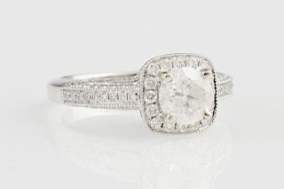 Lady's 18K White Gold Dinner Ring, with a one carat round diamond atop a border of small round diamonds, the shoulders and ed