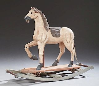 Child's Polychromed Carved Wood Riding Horse, 20th c., with a leather saddle, on iron wheels, now mounted in a later wooden r