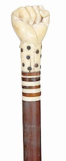 29. A Clinched Fist Nautical Cane- Mid 19th Century- A whale’s tooth carved fist protruding from a polka-dot decorated sleeve which has been skillfull