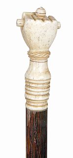 30. Whalebone Fist Cane- Mid 19th Century- A carved whale bone fist holding a baton in fine condition, ribbed whale bone upper collar, hardwood exotic