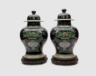 Pair of Chinese Iridescent Famille Noir Covered Baluster Jars, on carved wood stands