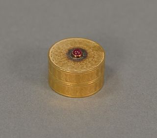 18 karat gold pill box set with red center stone. 10.9 grams ht. 7/16 inch, dia. 3/4 inch.