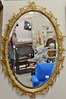 Oval gold framed mirror with carved leaf frame. 44" x 30"