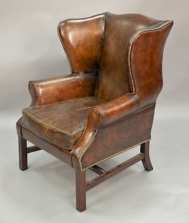 Distressed brown leather wing chair.