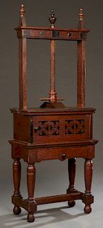 English Victorian Carved Mahogany Book Press, 19th c., the press mounted on a pierced door cupboard, on a base with a frieze drawer, on turned tapered
