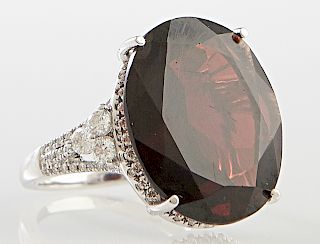 Lady's Antique 14K White Gold Dinner Ring, with a large oval approx. 15 carat faceted garnet atop a border of small round diamonds, the split shoulder