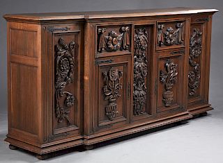 French Carved Oak Sideboard, early 20th c., the stepped breakfront top over two floral carved double panel cupboard doors with iron strap hinges flank