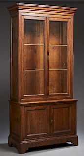 French Provincial Louis Philippe Style Carved Oak Bookcase Cupboard, c. 1880, the stepped rounded corner ogee crown over double glazed doors, on a bas