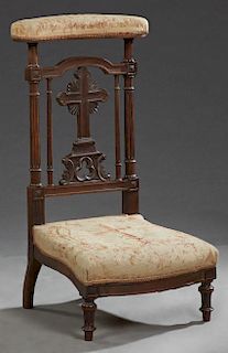 French Carved Walnut Prie Dieu, c. 1870, the curved upholstered armrest over a pierced cross splat, flanked by tapered reeded supports to a bowed seat