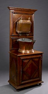 French Carved Walnut Lavabo, late 19th c., with a stepped crown over a geometric incised back, with a brass and copper double nozzle reservoir, and a 