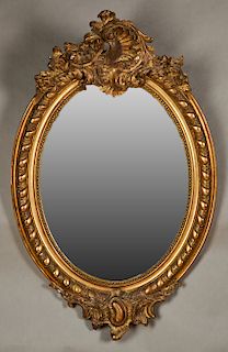 French Louis XVI Style Gilt and Gesso Oval Overmantle Mirror, late 19th c., the elaborate pierced floral crest over a wide frame with swirled bands ar