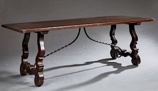 Spanish Provincial Carved Oak Farmhouse Table, late 19th c., the thick top on carved lyre form trestle bases joined by two twisted wrought iron stretc