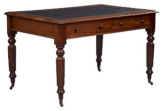 English Edwardian Carved Mahogany Writing Table, c. 1910, the inset gilt tooled leather top over two frieze drawers, on turned tapered reeded legs to 