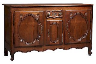 French Provincial Carved Oak Louis XV Style Sideboard, 20th c., the stepped rounded edge and corner top over a central frieze drawer above a cupboard 