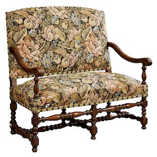 French Louis XIII Style Carved Walnut Loveseat, late 19th c., the arched upholstered back over scrolled arms and a cushion seat, on turned tapered leg