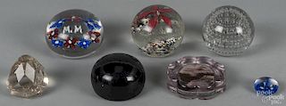 Seven assorted glass paperweights of varying sizes.
