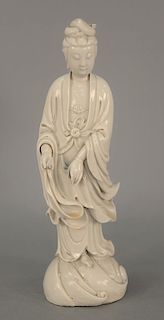 Blanc de Chine porcelain guanyin figure standing on tall rushing waves base, dressed in robe opening on chest showing beaded necklac...