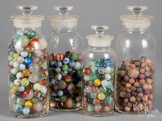 Four glass bottles with antique marbles