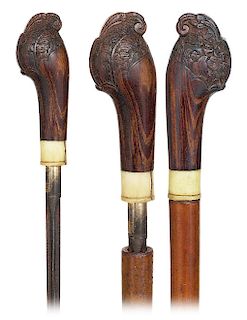 23. Sword Cane -Ca. 1900 -Large makassar ebony handle fashioned in a stylized pistol shape and partly engraved with floral extending in a flush set wi