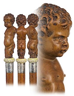 31. Figural Boxwood Cane -Ca. 1900 -Large boxwood vertical handle carved to depict a putti presented on a round and widening bone base with fine engra