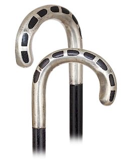 170. Art Deco Silver Cane -Ca. 1920 -Large and plain silver crook handle embellished with flush set ebony inlay, ebony shaft and a metal ferrule. Here