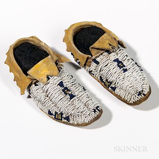 Cheyenne Beaded Child's Moccasins, c. 1900, with rawhide soles and hide uppers, beaded with multicolored geometric designs, and traces