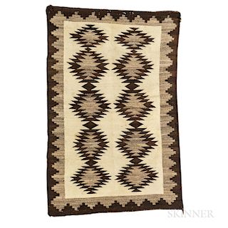 Navajo Regional Rug, c. 1920s, woven with natural and synthetic spun wool, the serrated diamond pattern with dark border on a natural g