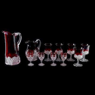 Juego de jarras y copas. Siglo XX. Elaboradas en vidrio transparente con tonos en rojo. Diseños mixtilíneos. Piezas: 11
