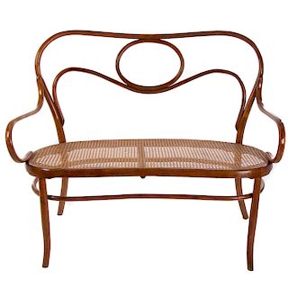 Love seat SXX. Estilo Austriaco. En talla de madera Respaldo semiabierto, asiento de bejuco tejido, chambrana oval y soportes lisos.