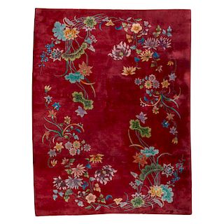 Alfombra. China, siglo XX. En lana y algodón. Decorada con enramadas florales en colores rosa, verde y naranja sobre fondo rojo.