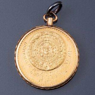 Moneda de 20 pesos. Elaborada en oro de 21.6k. Bisel y rehaza en oro amarillo de 10k. Peso: 21.0g.
