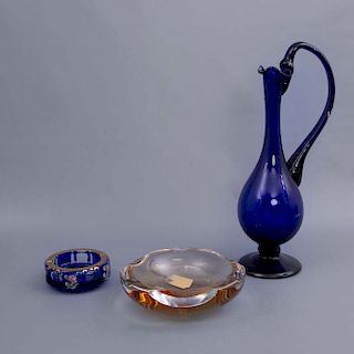 Lote mixto de 3 piezas. Elaborado en cristal. Consta de: cenicero color naraja, jarra color azul y centro de mesa color.
