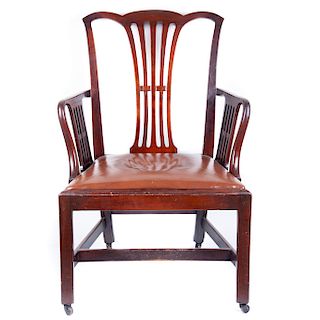 Sillón. S. XX . Elaborado en madera tallada de nogal. Respaldo abierto, asiento en tapicería de vinil color marrón y soportes de ruedas