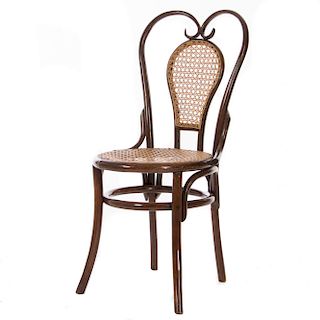 Silla. Siglo XX. En talla de madera. Con respaldo mixtilíneo y asiento en bejuco, chambrana circular y soportes lisos.