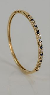 14 karat gold bangle bracelet, set with nine diamonds and ten sapphires. 
14.4 grams