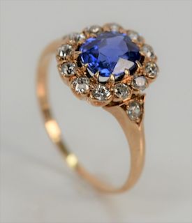 18 karat gold ring, set with blue sapphire of 1.03 cts. surrounded by twelve diamonds flanked by two diamonds.  size 4 3/4