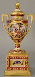 Meissen urn with cover having two gilt handles, 
urn with romantic oval panels and raised gold surround, on square pedestal base. 
h...